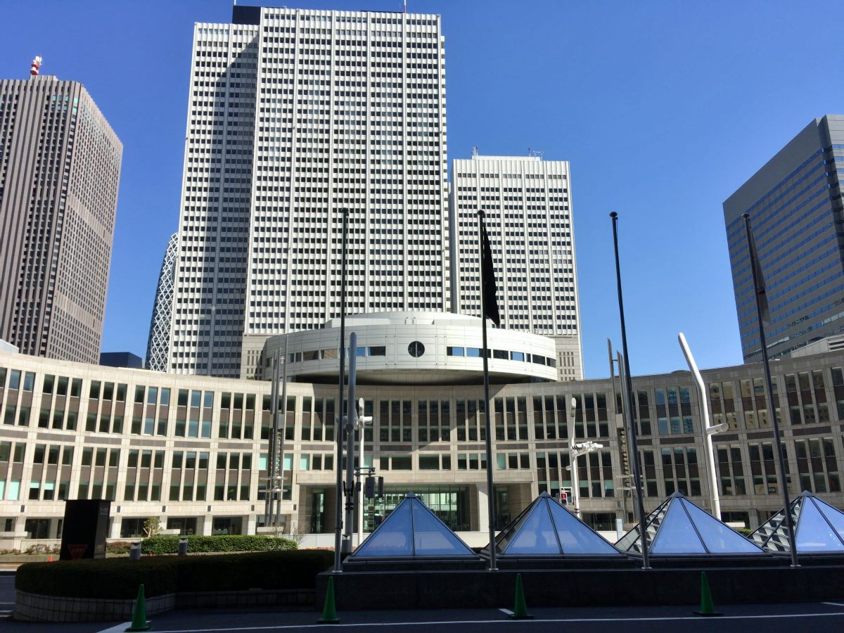 東京都庁の建物を正面から撮影した写真です。中央と左側、右側には高い建物があります。空は快晴です。